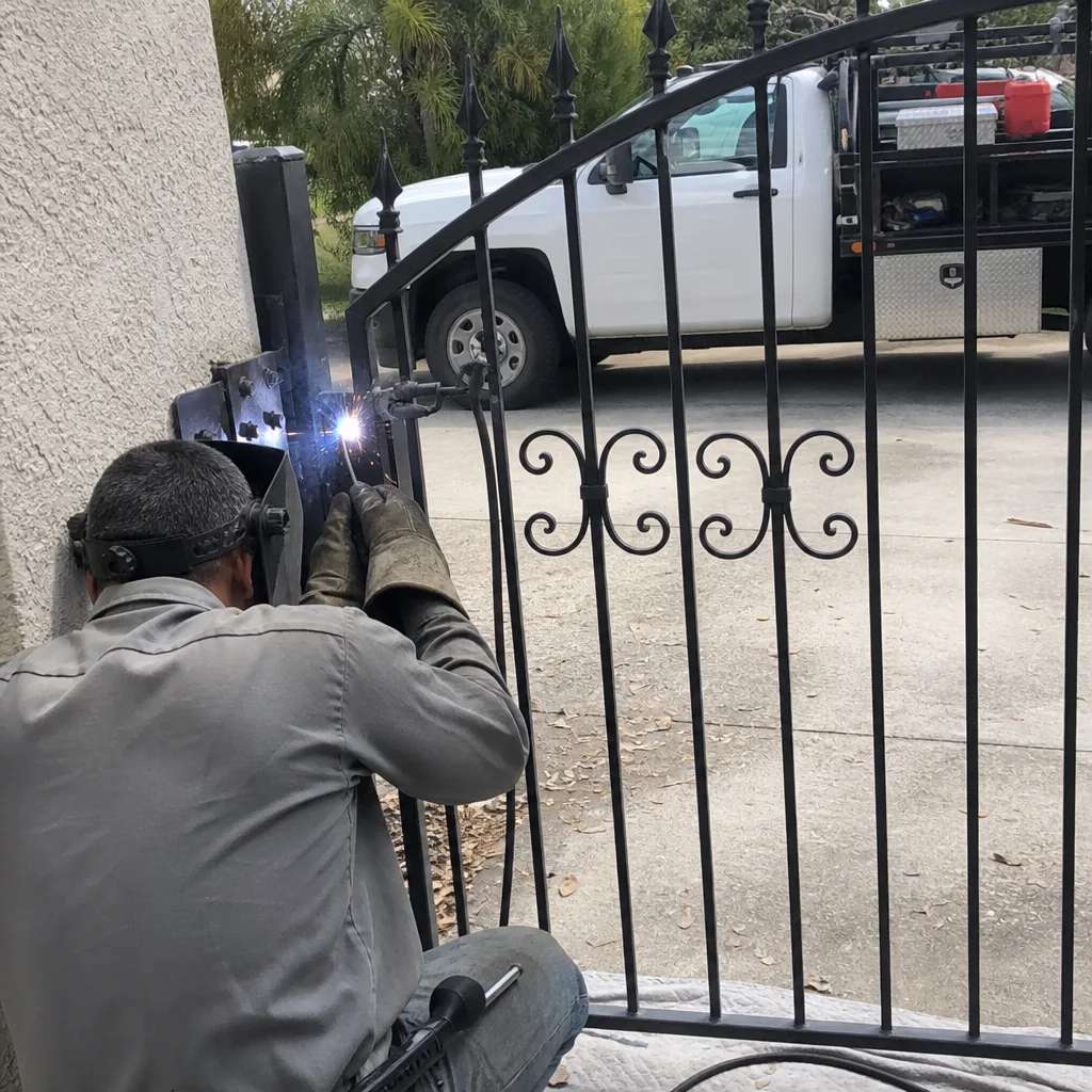 A professional welding a metal driveway gate during a repair service